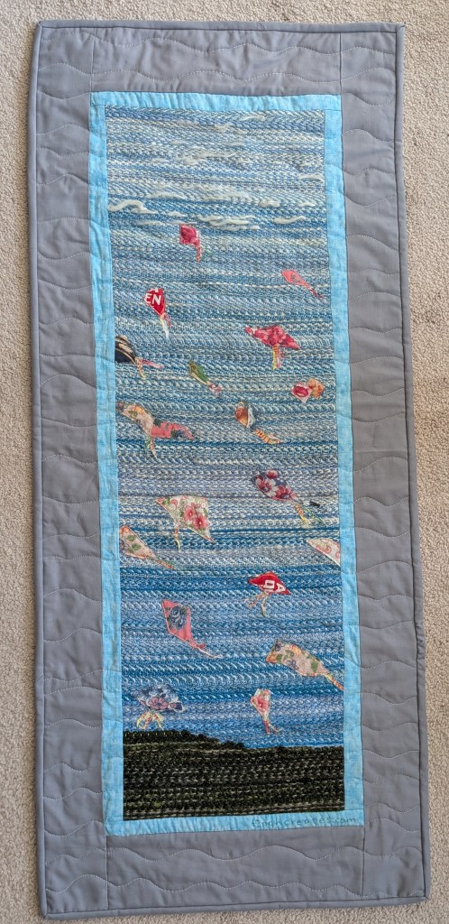 blue quilt with small applique shapes. bordered with light blue and gray